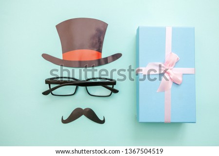 Happy Father's day concept. Sign of hat mustache with glasses gift box isolated on pastel blue background. Simple minimalism flat lay top view copy space. Man silhouette symbol