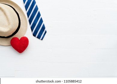 Happy Fathers Day Concept. Top View Of Red Tie, Handmade Red Heart And Hat On Bright White Pastel Wooden Table Background.