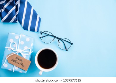 Happy Fathers Day Concept. Top View Of Blue Tie, Beautiful Gift Box, Coffee Mug, Glasses With LOVE DAD Text On Bright Blue Pastel Background.