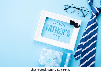 Happy fathers day concept. Top view of blue tie, beautiful gift box, white picture frame with Happy father's day text on bright blue pastel background. Flat lay. - Powered by Shutterstock