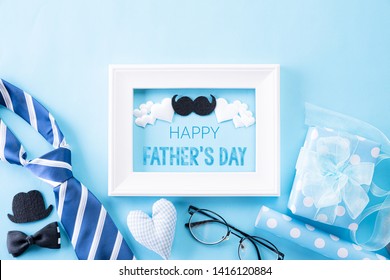 Happy fathers day concept. Top view of blue tie, beautiful gift box, white picture frame with Happy father's day text on bright blue pastel background. Flat lay. - Powered by Shutterstock