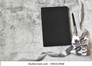 Happy father's Day. Diary, pen and gift box on a gray concrete background. Holiday concept. Copy space, flat lay.