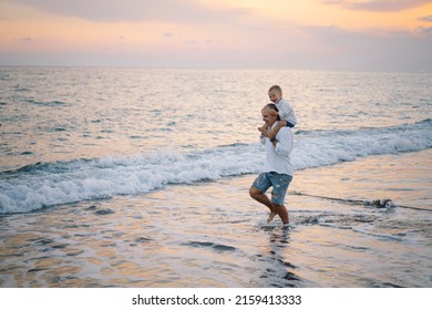 Happy Father's Day. Father And Baby Play On The Beach. Dad And Him Child Together Enjoying Sunset. Loving Single Father Hugs Cute Little Son.