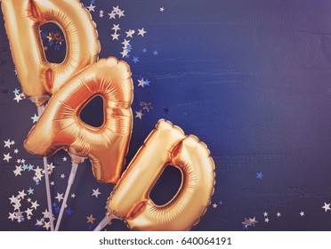 Happy Fathers Day Gold Baloons For The Word, Dad, On Dark Blue Wood Background With Silver And Blue Scattered Glitter Stars, With Applied Retro Style Filters.