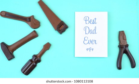 Happy Father's Day Overhead Of Chocolate Tool Set With Best Dad Ever Greeting Card On Pale Blue Aqua Table.