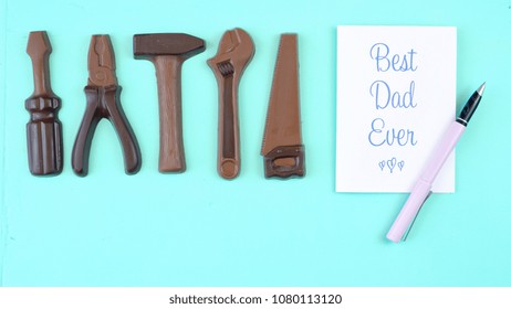 Happy Father's Day Overhead Of Chocolate Tool Set With Best Dad Ever Greeting Card On Pale Blue Aqua Table.