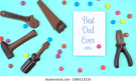 Happy Father's Day Overhead Of Chocolate Tool Set With Best Dad Ever Greeting Card On Pale Blue Aqua Table.