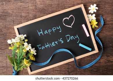 "Happy father's day" sign on chalkboard decorated with ribbon and flower on wooden table top - Powered by Shutterstock