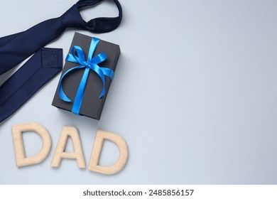 Happy Father's Day. Word Dad made with wooden letters, gift and tie on light background, flat lay. Space for text - Powered by Shutterstock