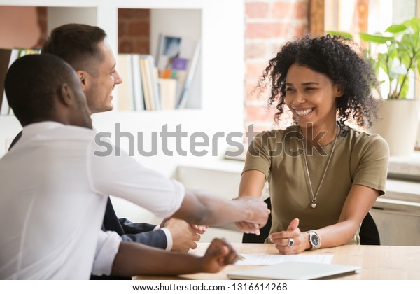 Happy female african vacancy candidate shaking\
hand of hr recruiting manager congratulating hired applicant with\
handshake, successful interview winner make good first impression\
got new job concept