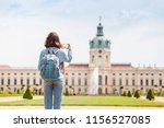 Happy female asian tourist in the baroque garden in front of the ancient architecture of royal Charlottenburg palace. Sightseeing and travel destinations in Berlin and Germany concept