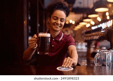 Happy female barista serving beer at bar counter. - Powered by Shutterstock