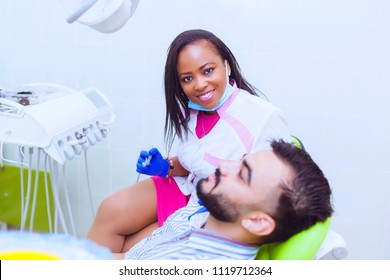 Happy Female Black Dentist Talking To Patient At Desk In Clinic