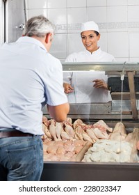 Happy Female Butcher Selling Chicken Meat To Male Customer In Butchery