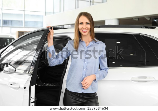 Happy female buyer\
near new car in salon
