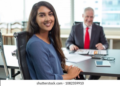 Happy female candidate after successful job interview. Young Indian woman in casual smiling at camera after talking to mid adult business man in meeting room. Meeting or employment concept