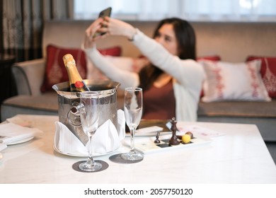 Happy female celebrate birthday with champagne and cakes. Female having fun doring her birthday in hotelroom. Young beautiful woman taking her selfie photo and Celebrating a birthday in the bedroom.