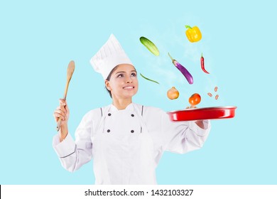 Happy Female Chef Throwing Food Ingredients In A Frying Pan While Cooking In The Studio