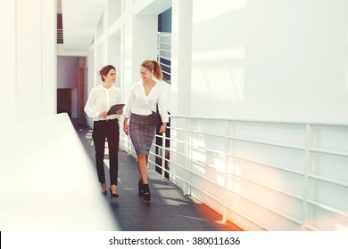 Happy Female Colleagues Planning The Schedule Of Work For Next Project Via Digital Tablet While Walking In Office Interior, Women Intelligent Lawyers Laughing At Funny Video On Touch Pad During Break