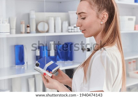 happy female cosmetologist is holding preparats in light and minimalistic beauty cabinet Imagine de stoc © 