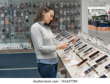 Happy Female Customer Choosing Smartphone In The Mobile Phone Shop. Difficult Decision. Various Choice