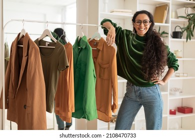 Happy Female Designer Standing Near Clothing Rail Smiling To Camera Presenting New Collection Posing In Modern Showroom, Smiling To Camera. Fashion And Style, Design Career Concept - Powered by Shutterstock