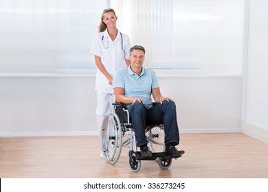 Happy Female Doctor Carrying Male Patient On Wheelchair - Shutterstock ID 336273245