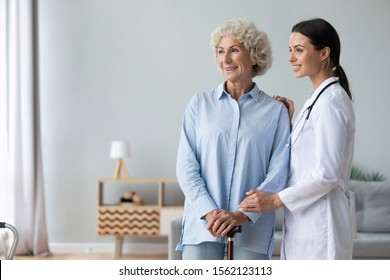 Happy Female Doctor Nurse Carer Provide Old Woman Healthcare Medical Services Assisting Smiling Senior Grandma Hold Walking Stick Looking Away Dreaming Of Good Future, Elder People Homecare Concept