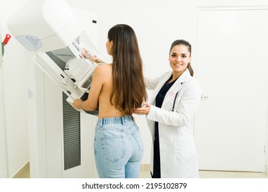 Happy Female Doctor Or Radiologist On A Lab Coat Smiling While Helping A Young Woman During A Mammogram Medical Exam