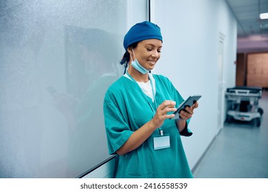 Happy female doctor using smart phone on a break in the hallway at medical clinic. Copy space.  - Powered by Shutterstock