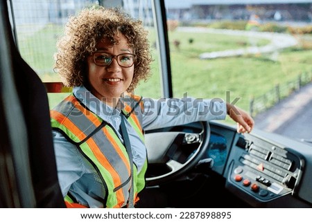Happy female driver in public bus looking at camera.
