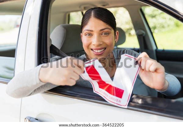 happy\
female driver tearing up her learner driver\
sign