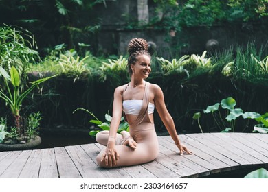 Happy female enjoying yoga practice stretching in asana and resting in retreat, cheerful woman have outdoors training for flexibility feeling vitality and wellbeing harmony during meditation at nature - Powered by Shutterstock