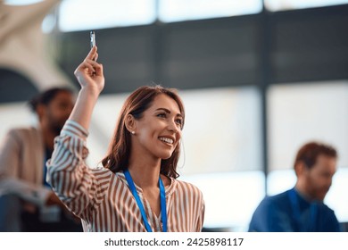 Happy female entrepreneur asking a question from the audience during a  business conference in convention center. Copy space. 