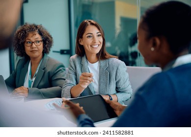 Happy female entrepreneur communicating with coworkers on a meeting in the office.