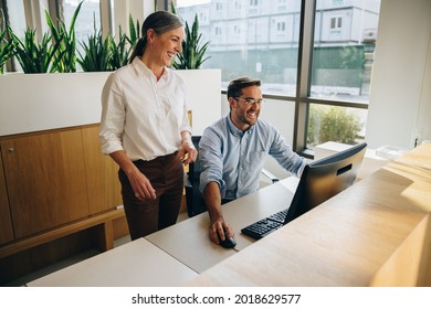 Happy Female Executive Supervising Her Coworker Work On Computer. Manager And Employee Looking At Computer And Smiling.