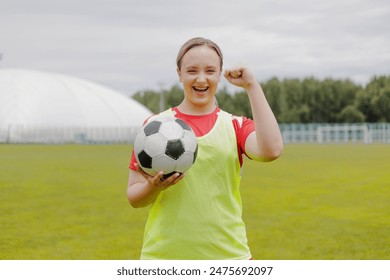 Happy female football player in sportwear celebrating victory, holding soccer ball. - Powered by Shutterstock