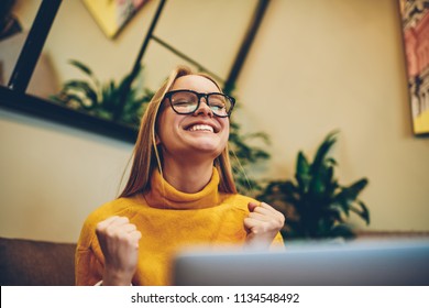 Happy female freelancer feeling excited of completed program project on laptop computer connected to wifi indoors, smiling woman student celebrating achievement on course work on modern netbook