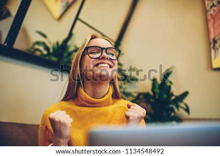 Happy female freelancer feeling excited of completed program project on laptop computer connected to wifi indoors, smiling woman student celebrating achievement on course work on modern netbook