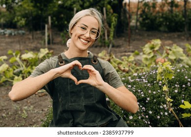 Happy female gardener making a hearth shape with her hands.