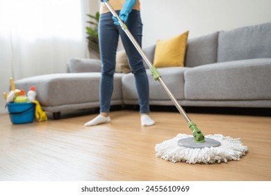 happy Female housekeeper service worker mopping living room floor by mop and cleaner product to clean dust.