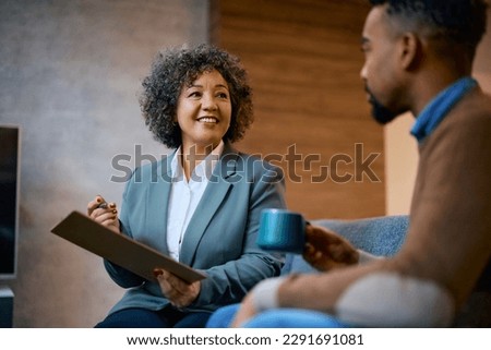 Happy female insurance agent advising African American client during a meeting in the office.