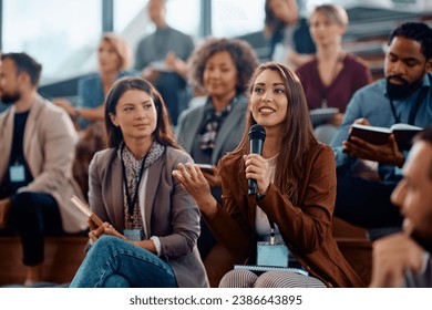 Happy female manager asking a question from the audience while participating in business seminar at convention center. - Powered by Shutterstock