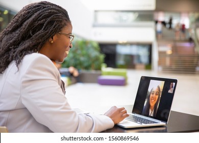 Happy female office friends talking through video call. Business women using digital devices for video chat. Internet connection concept