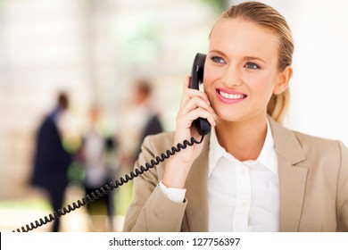 Happy Female Office Worker Talking On Landline Phone