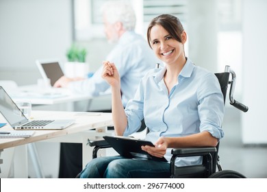 Happy Female Office Worker In Wheelchair Holding A Clipboard And Smiling At Camera, Disabled People Support At Workplace