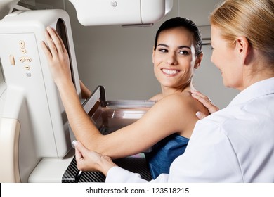 Happy female patient looking at doctor while undergoing mammogram x-ray test