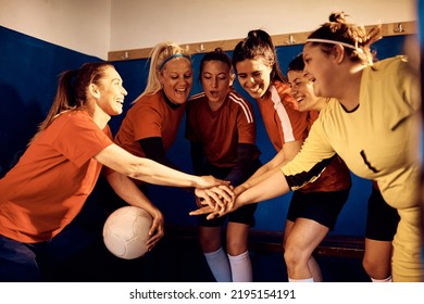 Happy female players supporting each other while gathering hands in unity in locker room. - Powered by Shutterstock