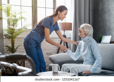 Happy female professional caregiver taking care of elderly woman at home