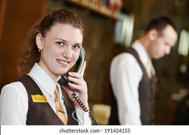 Happy Female Receptionist Worker With Phone Standing At Hotel Counter